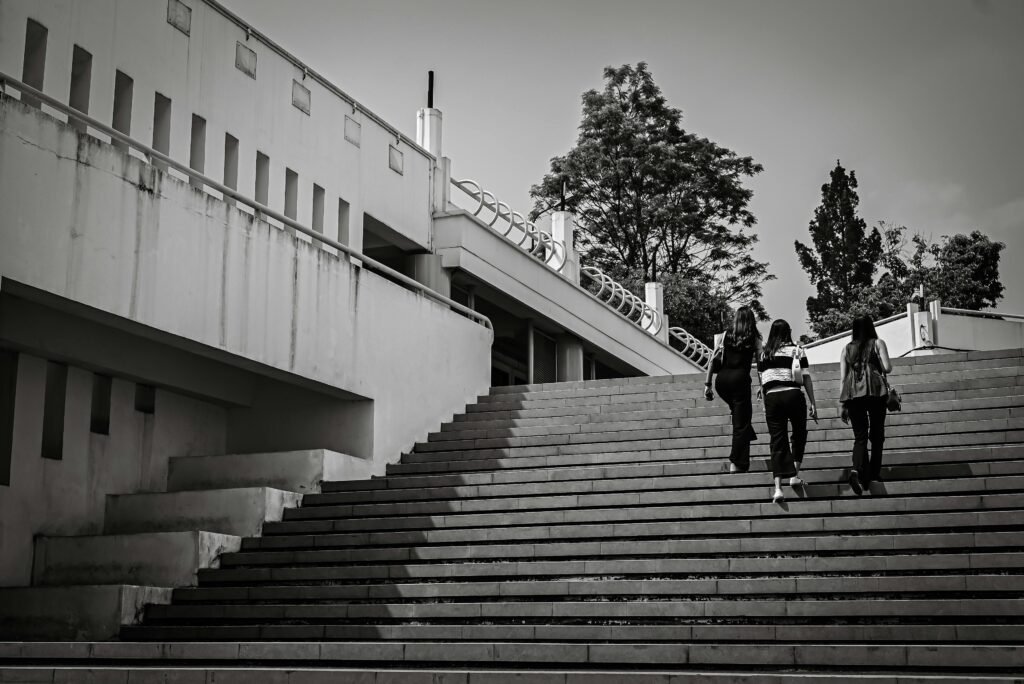 Black and white photo of a modern campus architecture with people ascending stairs outdoors.